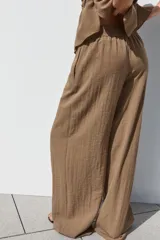 Pantalón marrón de tiro alto con cintura elástica, bolsillos delanteros y pernera ancha.
