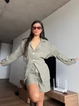 Blazer verde con rayas verticales blancas, de corte holgado, con cuello clásico, cierre frontal con botones y mangas largas.