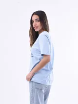 Remera negra de algodón con cuello redondo y mangas cortas. Estampado frontal con la frase "World Tour Vacation State of Mind" en letras de colores y un pequeño dibujo de una palmera.