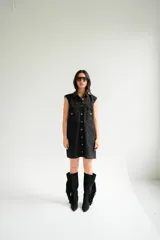 Vestido corto de jean gris con botones frontales, sin mangas, con cuello camisero y bolsillos en el pecho.