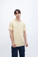 Remera color crema con cuello redondo y media cartera con dos botones. Tiene un bordado en la espalda.