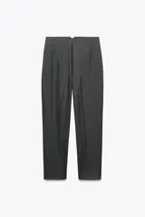 Pantalón tobillero color gris claro, de tiro alto, con bolsillos delanteros de vivo y cierre frontal con cremallera, botón interior y gancho metálico.