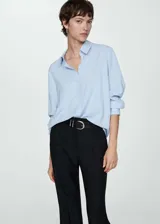 Camisa celeste de tejido fluido, corte recto, manga larga con puños abotonados, cuello camisero y cierre frontal con botones.