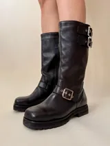 Botas de cuero negro, de caña media, con punta cuadrada, suela track y hebillas metálicas plateadas.