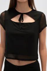 Top negro de poliéster con mangas cortas, cuello redondo, corte ajustado y abertura en el pecho.