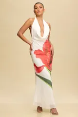Vestido largo blanco con estampado de una flor roja, escote halter y espalda descubierta.