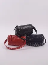 Bandolera color rojo de cuero con tachas plateadas. Tiene dos asas desmontables, una corta con tachas para llevarla en la mano o al hombro y una larga para llevarla al hombro o cruzada. Tiene bolsillo interior con cierre y forro.