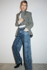 Jeans de tiro alto, estilo balloon leg, largo completo. Denim azul claro con efecto lavado ácido o 'acid wash'. Presenta cinco bolsillos y cierre frontal con cremallera y botón.