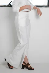 Conjunto de dos piezas color blanco, compuesto por un blazer corto de mangas 3/4 y un pantalón wide leg con tajo lateral en el dobladillo.