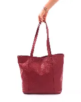 Bolso tipo tote de cuero natural color rojo oscuro, con asas largas para llevar al hombro. Presenta una textura granulada y un diseño simple y espacioso.