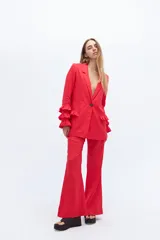 Conjunto de blazer y pantalón acampanado color rojo. El blazer es de corte clásico con solapas y un botón, y tiene volados en las mangas. El pantalón es de tiro alto y pierna acampanada.