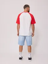 Remera blanca con mangas raglán negras y estampado frontal con el logo de Rusty en azul.