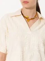 Remera color crema con textura de toalla con diseño floral, cuello camisero y mangas cortas.