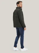 Campera acolchada verde militar de Tommy Hilfiger, con cuello alto, cierre de cremallera, dos bolsillos delanteros con cremallera y logo de Tommy Hilfiger bordado en el pecho.