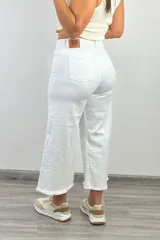 Pantalón jean blanco de corte culotte, con tiro alto, pierna ancha y terminación desflecada.
