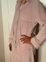Pijama celeste de terciopelo, compuesto por una camisa de manga larga con botones y vivo blanco, bolsillo en el pecho y un pantalón recto con elástico en la cintura.
