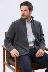 Campera tejida de lana color gris oscuro, con cuello alto, cierre metálico frontal y bolsillos laterales. Presenta detalles en cuero y un logo bordado en el pecho.