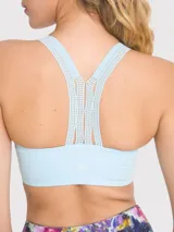 Top deportivo celeste con soporte medio, almohadillas removibles, tirantes anchos y espalda deportiva. Presenta detalles de encaje en la banda inferior y en los tirantes.