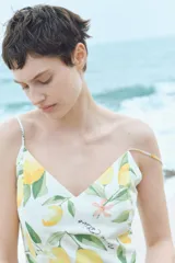 Vestido midi de algodón con estampado de limones, breteles finos ajustables, escote en V y espalda fruncida. Tiene corte en la cintura y falda acampanada.