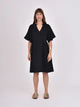 Vestido negro de corte suelto, con escote en V y mangas cortas amplias.