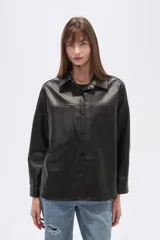Sobrecamisa negra de efecto cuero, con cuello camisero, botones frontales y dos bolsillos de parche con solapa en el pecho. Presenta un calce holgado.