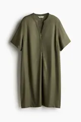 Vestido túnica a la rodilla en tejido liviano de viscosa color verde oliva con cuello mao y abertura en V. Modelo de corte holgado con hombros levemente caídos, mangas cortas y bajo recto con tajos laterales.