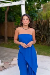 Conjunto de dos piezas color beige claro, compuesto por un top strapless con bajo asimétrico y un pantalón ancho de tiro alto.