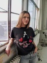 Remera negra de manga corta con estampa de la serie Emily in Paris con corazones rojos.