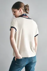 Remera color crema de algodón con cuello y mangas con ribete azul marino. Estampado frontal con la frase "Rock the Music" en letras negras con detalles de estrellas.