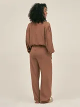 Pantalón palazzo negro de crepe con cintura elastizada, bolsillos laterales y terminaciones con logo en cobre.