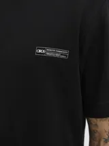 Remera negra de manga corta y cuello redondo, con un estampado gráfico en la espalda que muestra una escena urbana con edificios y texto que incluye "Metropolitan Scenes 1990" y el logo "JACK&JONES WORLDWIDE".