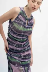 Vestido midi de microtul estampado tipo batik en tonos lavanda, verde y negro. Diseño ajustado con frunces y forro en todo el cuerpo. Falda transparente con terminación en picos.