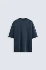 Camiseta azul marino de corte holgado, confeccionada en algodón con cuello redondo y mangas cortas. Presenta un efecto de lavado que le da una apariencia única.