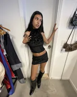 Top negro con escote halter que se ata en la nuca y la espalda, con detalle de nudo en la parte baja de la espalda. La prenda tiene un tejido con textura de terciopelo o jacquard con diseño de arabescos.