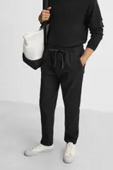 Pantalón de jogging color beige confeccionado en tejido de mezcla de algodón. Cuenta con cintura elástica ajustable con cordón, bolsillos frontales y traseros.