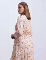 Vestido midi estampado con flores y mandalas en tonos naranja, rojo y celeste, con escote en V, mangas 3/4 con puños fruncidos, cintura elastizada con lazo y ruedo irregular.