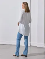 Camisola blanca de manga tres cuartos, marca Rio & Rian. Cuello con solapa y abertura central con botones. Manga con detalle fruncido.