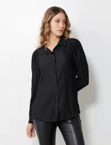 Camisa negra de satén plisado con cuello con solapa y abertura central con botones.