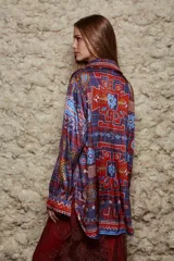Camisa holgada con estampado geométrico en tonos azules, rojos y marrones. Tiene cuello solapa, mangas largas y cierre abotonado.