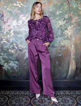 Pantalón palazzo de tiro alto color violeta, de satén. Tiene pretina delantera con pasadores, botón y cierre, pretina trasera elastizada y bolsillos verticales delanteros.