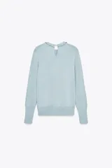 Jersey celeste de punto con cuello redondo adornado con abalorios joya y manga larga. Tiene cierre en la espalda con abertura y botones.