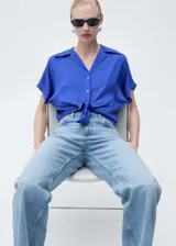 Camisa color crema de manga corta con tejido satinado, corte regular, cuello camisero y cierre delantero con botones.