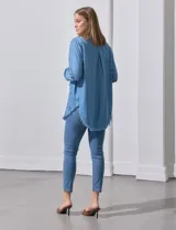 Camisa celeste de tencel con cuello con solapa, escote en V, abertura central con botones, bolsillo aplicado y ruedo desflecado.