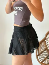 Minifalda negra de encaje con forro interior y cinturón con hebilla dorada.