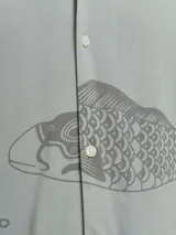 Camisa de viscosa LENZING™ ECOVERO™ color verde con estampado de peces y olas en gris, cuello resort, mangas cortas y corte relajado.