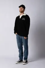 Sweater de punto verde con cuello polo color crema y bordado frontal con texto en blanco.