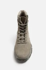 Zapatilla botín color gris, con combinación de piezas de piel y otros materiales en el corte. Cordonera con siete pasados y suela con volumen y diseño de textura.