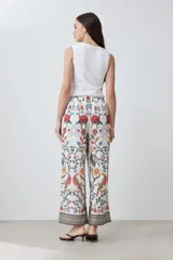 Pantalón de vestir blanco con estampado floral en tonos naranja, verde y rojo. Presenta un corte recto y cintura elástica. Incluye una chaqueta haciendo juego.