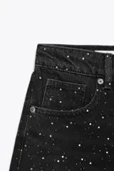 Short de jean negro con lavado gastado y pequeñas estrellas blancas estampadas. Tiene tiro alto, corte recto y terminación desflecada.