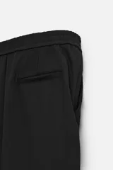 Pantalón negro de corte recto con cintura elástica, bolsillos laterales y un bolsillo trasero de ojal.